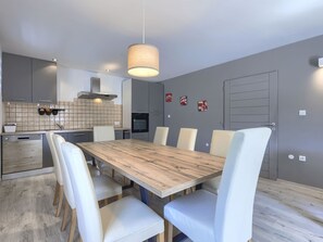 A modern kitchen with grey cabinets, a wooden dining table, and white chairs. - Vacation home A.E.M by Interhome (Medulin/Šišan)
