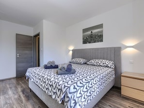 A modern bedroom with a large bed, a cityscape view, and a wooden floor. - Vacation home A.E.M by Interhome (Medulin/Šišan)