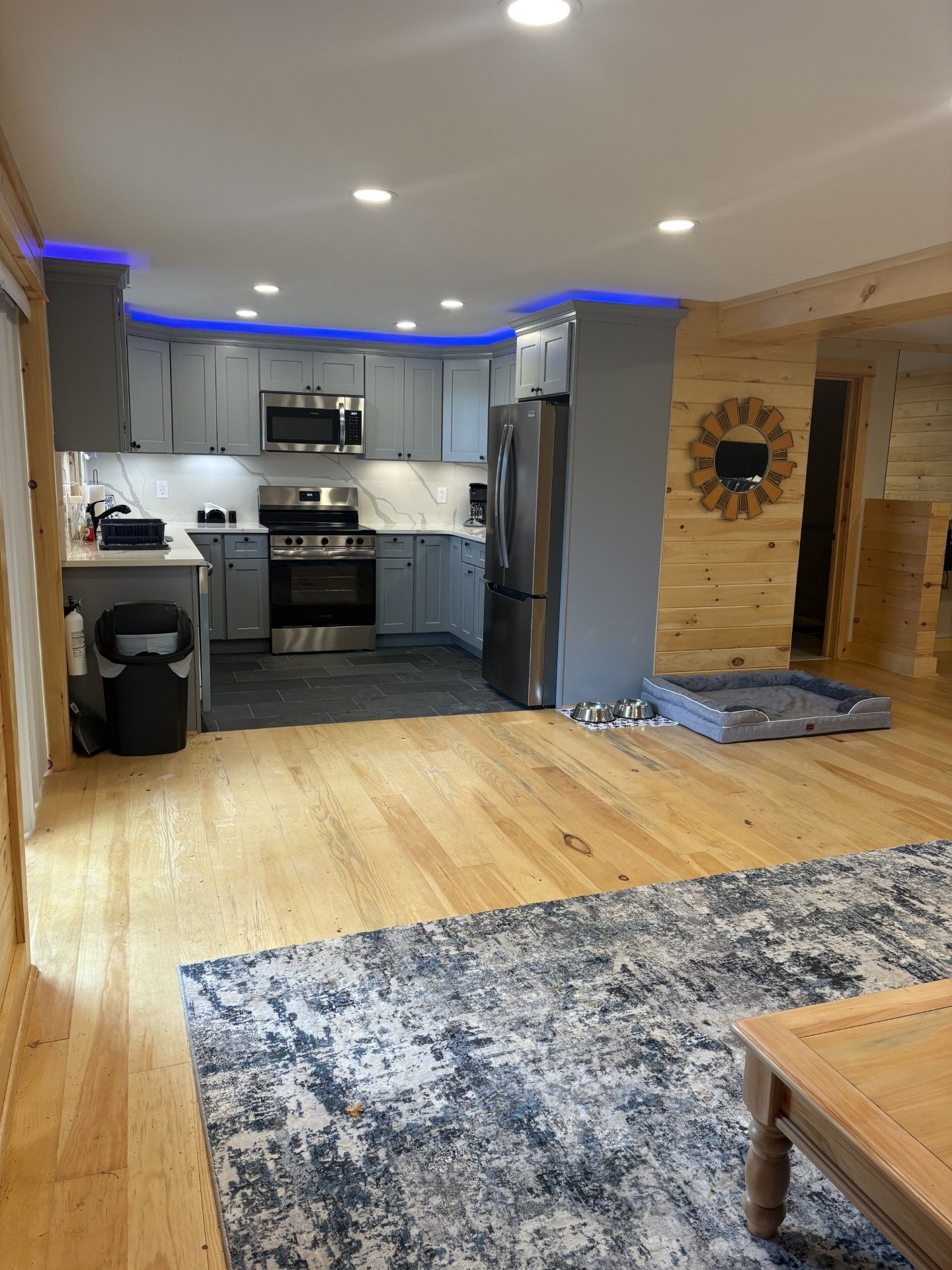 Een moderne keuken met grijze kastjes, roestvrijstalen apparatuur en een houten vloer.