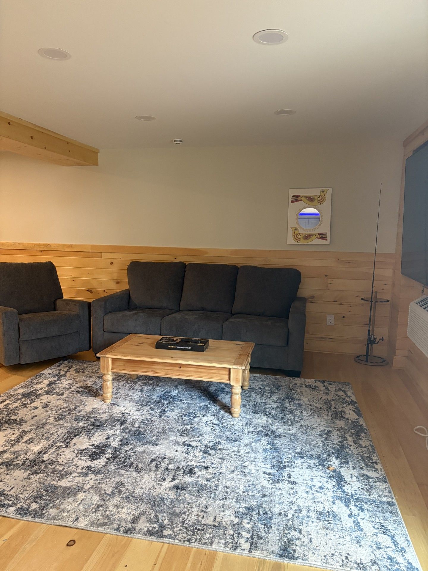 Una sala de estar con un sofá gris, una mesa de centro de madera y un tapete estampado.