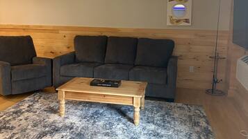 Una sala de estar con un sofá gris, una mesa de centro de madera y un tapete estampado.