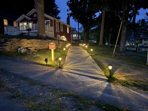 En indkørsel til et bolighus med en stenvæg, en postkasse og et vejskilt.