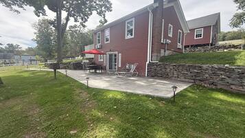 Una casa roja con un patio, mobiliario exterior y un muro de piedra.