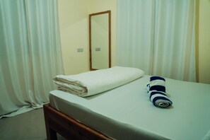 A hotel room with a bed, a folded white towel, and a rolled towel with stripes. - One Bedroom Apartment (Arusha)