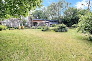 A stone building with a covered porch and a grassy yard. - The Charm of the Two Rivers (BELLE ISLE EN TERRE)