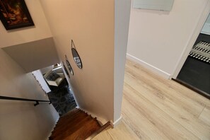 Eine Treppe mit hölzernem Geländer, einer weißen Wand und einem gemusterten Teppich am Fuß.