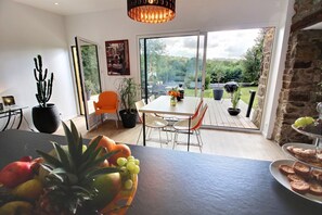 Un coin repas avec une table, des chaises et un panier de fruits.
