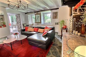 A living room with a sectional sofa, a small table, and a fireplace. - The Charm of the Two Rivers (BELLE ISLE EN TERRE)