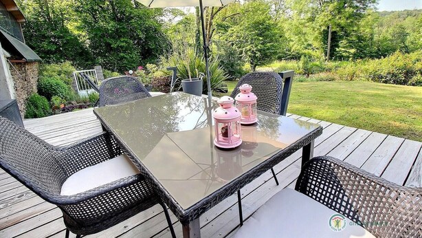 Eine Terrasse im Freien mit einem Glastisch, Korbstühlen und pinkfarbenen Laternen.