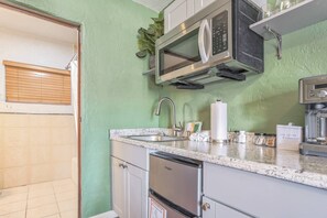 A kitchen with a built-in microwave, a sink, and a dishwasher. - San Ayre Court - The Green Room (1) (Colorado Springs)