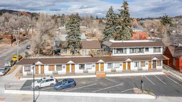 A motel with a parking lot, multiple-story buildings, and a mountainous backdrop.