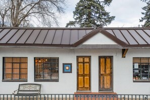 Rakennuksessa on harjakatto, suuret puiset ovet ja ulkona penkki.