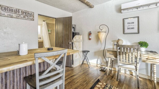 A modern kitchen with a wooden countertop, a sink, and a dining area with a wooden table and chairs. - The Birch Room | Pet-Friendly Studio Near Manitou (Colorado Springs)