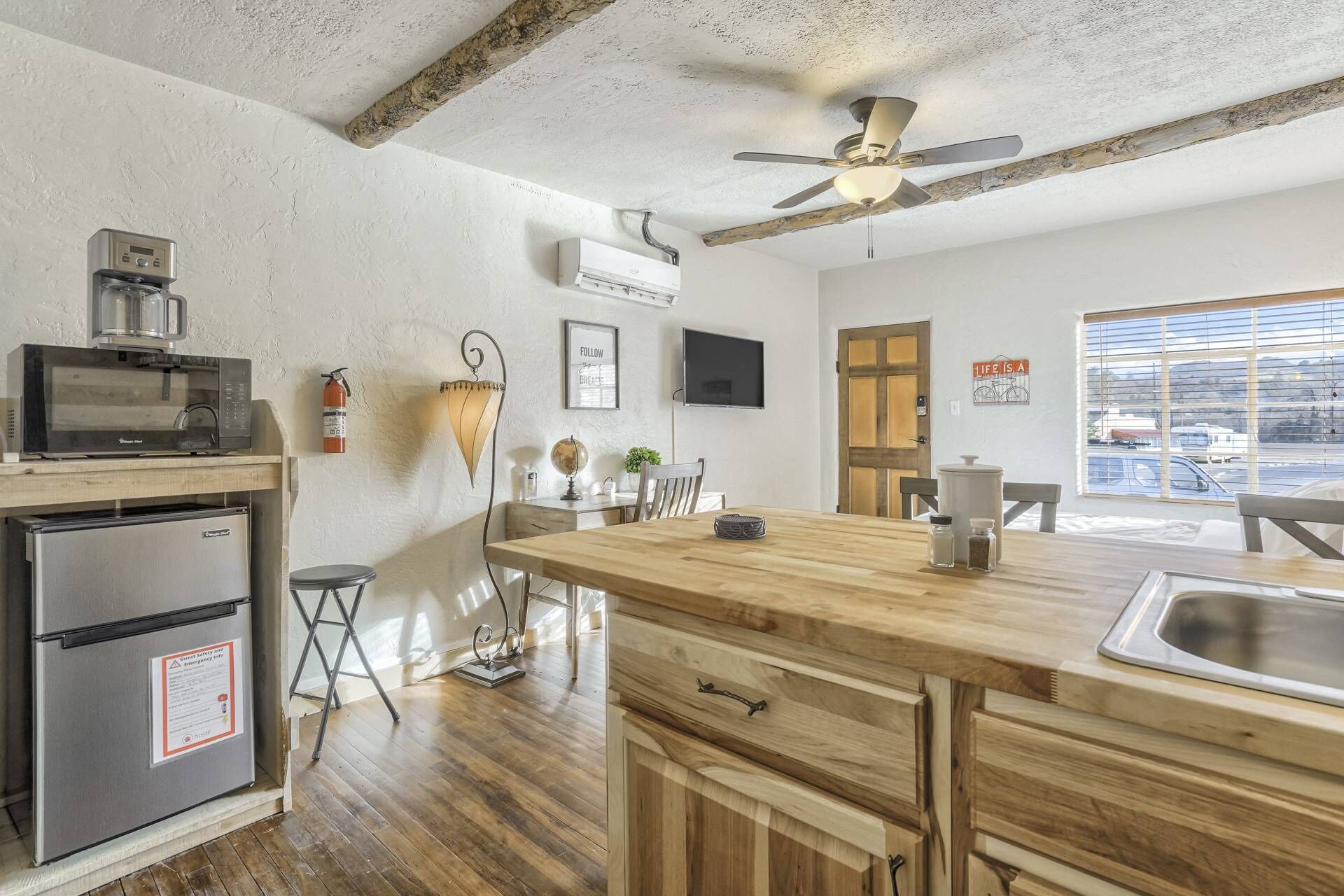 Una cocina con encimera de madera, microondas, refrigerador, ventilador de techo y ventana con vistas.
