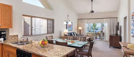 A spacious kitchen with a granite countertop, a dining area with a table and chairs, and a ceiling fan.