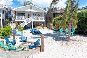 A beachfront property with a covered patio area, outdoor seating, and a stone fire pit. - Eikos Beach House - 4 BR / 3 BA - Heated Pool / Spa (Treasure Island)