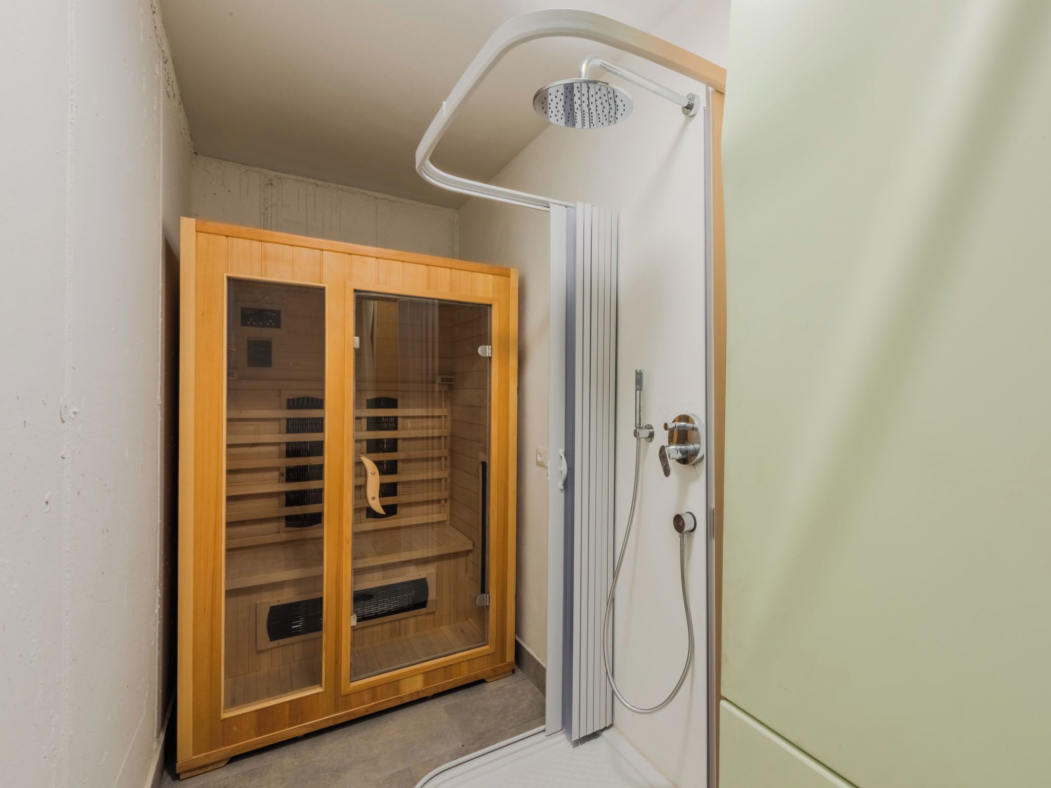 A walk-in closet with wooden shelving and a shower area with a glass door.