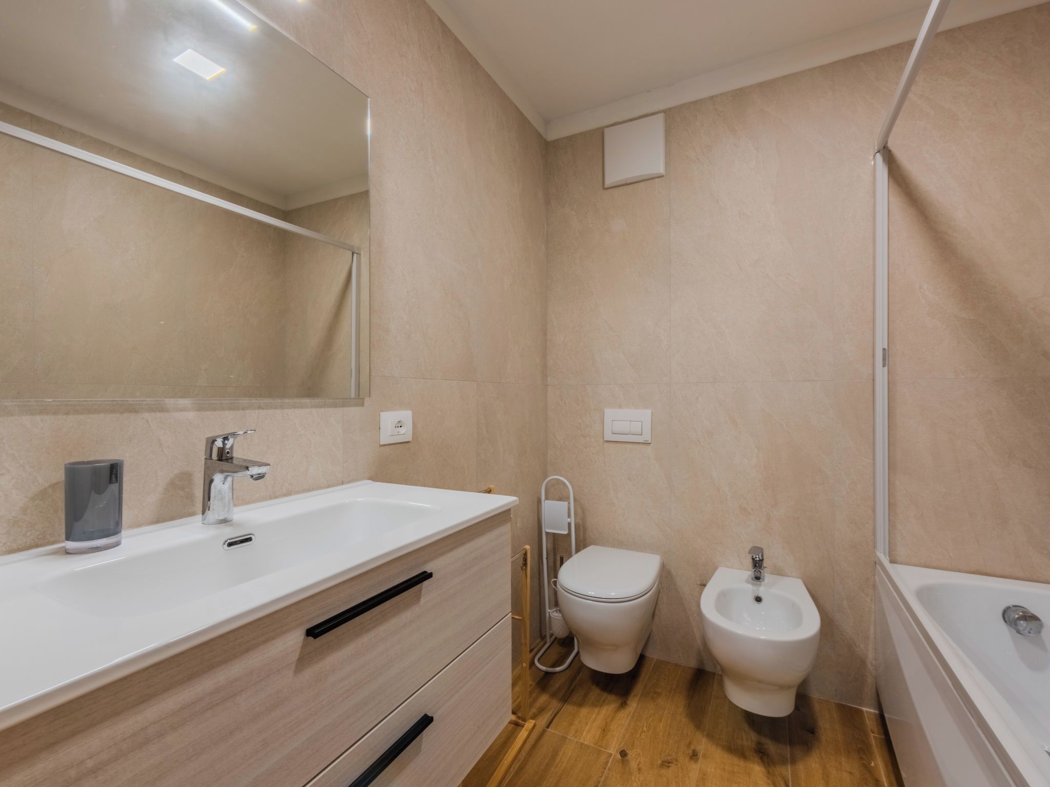 A modern bathroom with a white sink, mirror, and a bidet.