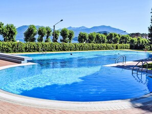 Ein Swimmingpool mit klarem, blauem Wasser, umgeben von einer gepflasterten Terrasse und gesäumt von ordentlich geschnittenen Hecken.