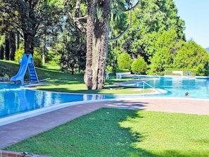 A swimming pool with a slide, surrounded by grass and trees. - Hermitage by Interhome (Porto Valtravaglia)