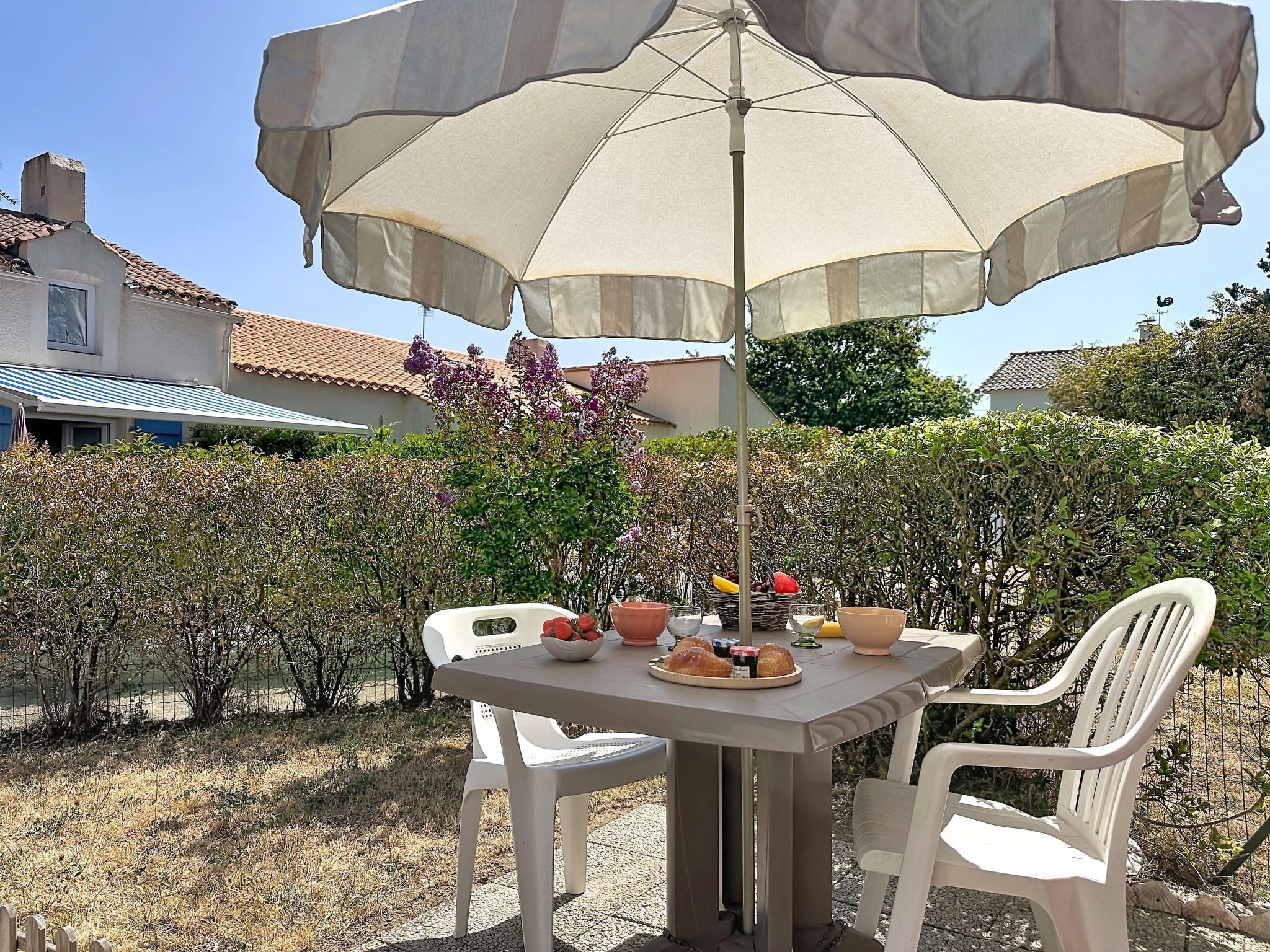 Un espace extérieur aménagé pour prendre les repas, avec une table, des chaises et un parasol.