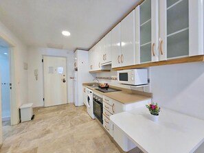 A compact kitchen with white cabinets, a microwave, a washing machine, and a sink. - Apartamento Alba 7 by Interhome (Cartagena)