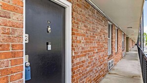 Un edificio in mattoni con una porta nera, una piccola finestra e un cancello in metallo.