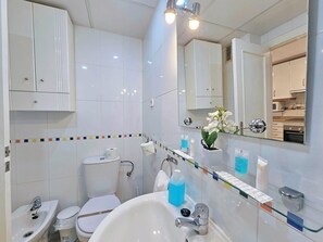Un baño moderno con inodoro, lavamanos y espejo.