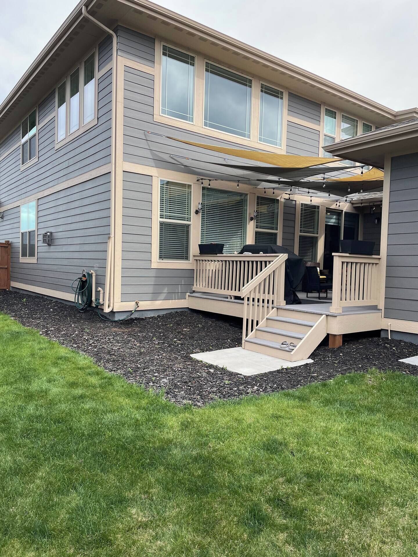A two-story house with a covered porch, a small outdoor seating area, and a visible hose for outdoor use.
