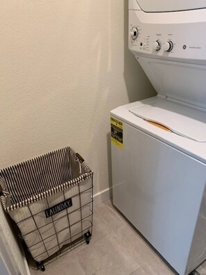 Ein Wäschekorb mit dem Aufdruck 'LAUNDRY' neben einer weißen Waschmaschine.