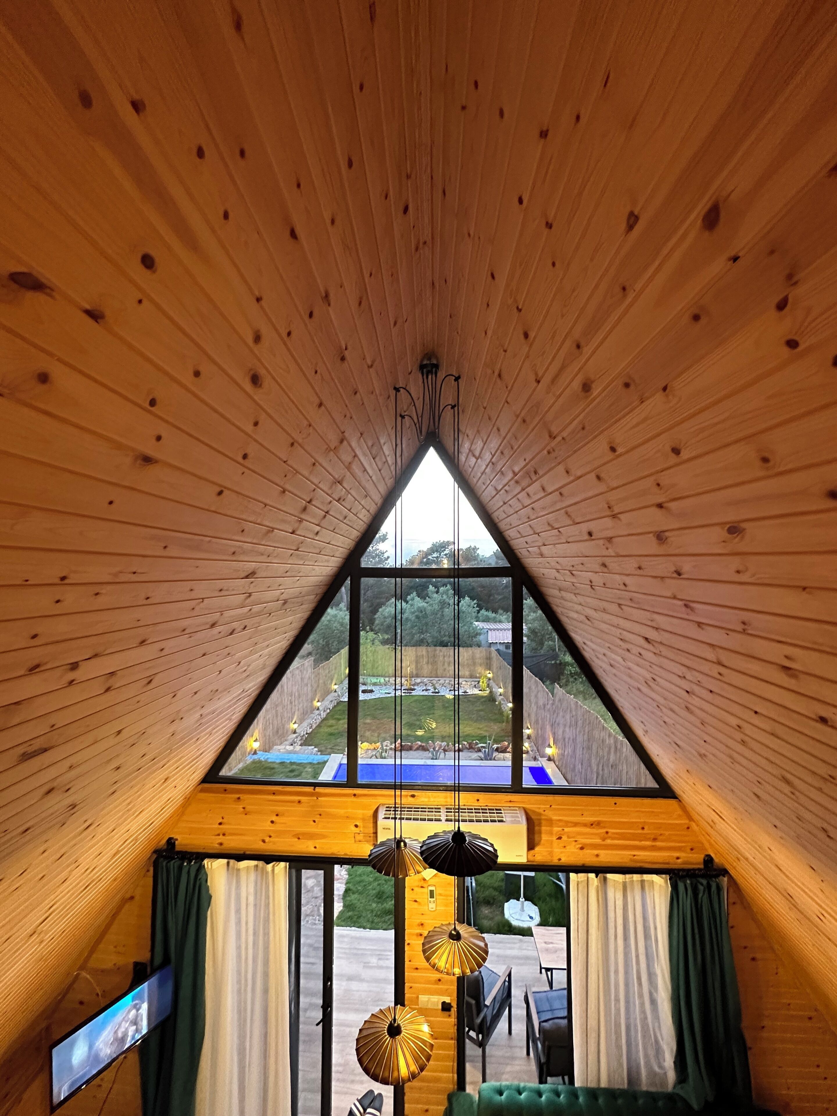 A room with a sloped ceiling, a large window, and a view of an outdoor area.