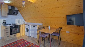 A compact kitchen with a washing machine, a dining area with chairs, and a flat-screen TV mounted on the wall. - Ölüdeniz araçla 10 dakika kelebekler vadisine 5 dakika villa likya yolu üzerinde (Uzunyurt)