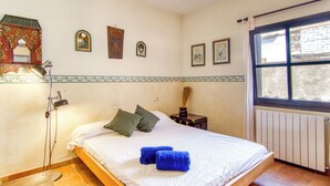 Un dormitori amb un llit individual, una làmpada de nit, un radiador i una finestra amb vistes.