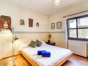 Een slaapkamer met een enkel bed, een bedlamp, een radiator en een raam met uitzicht.