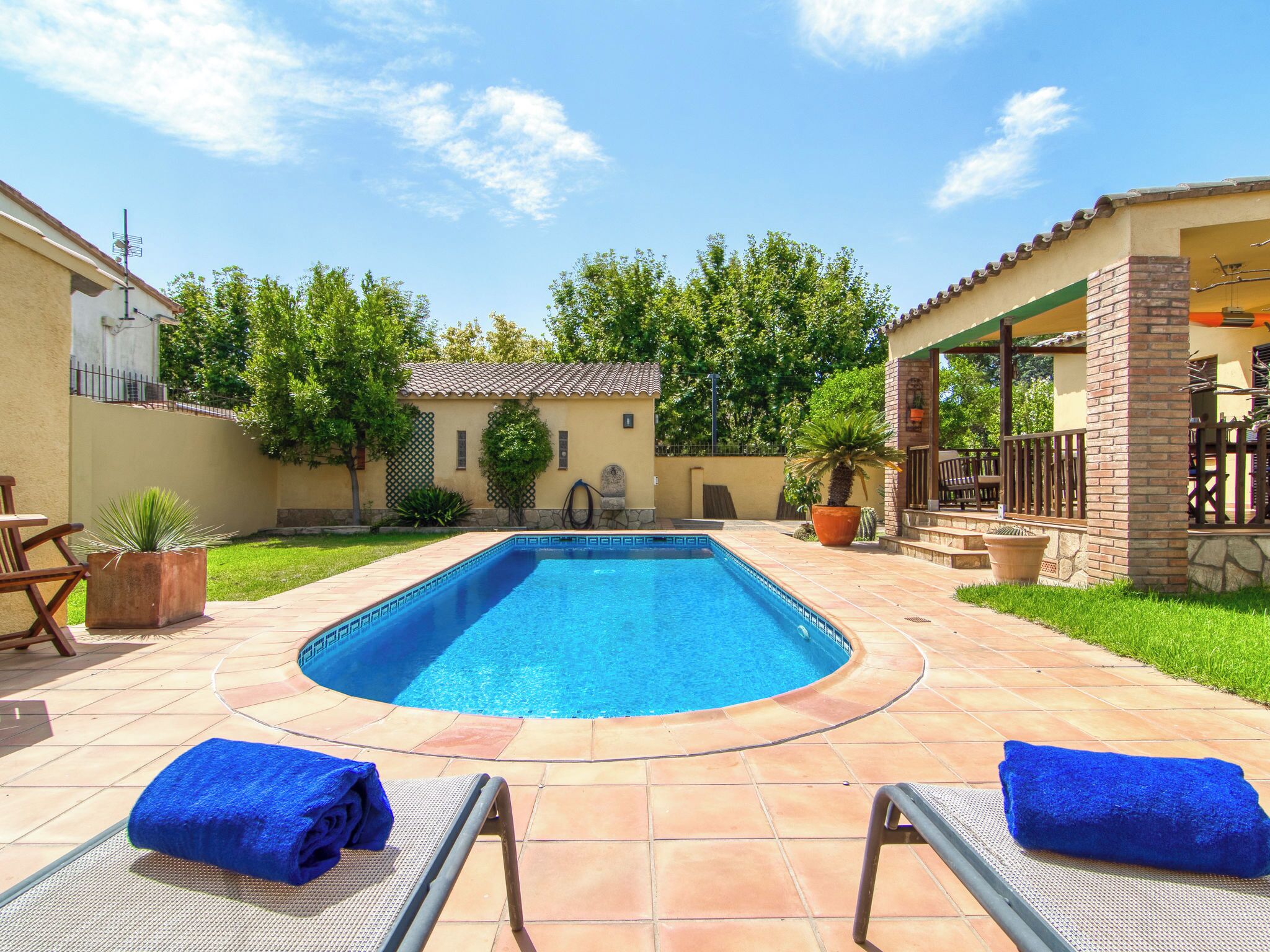 A swimming pool with two lounge chairs and a covered patio area.