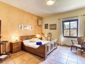 Ein Schlafzimmer mit einem hölzernen Bett, Nachttischen, einem Sessel und einem Fenster mit Vorhängen.