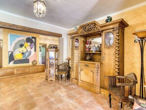 A spacious room with a tiled floor, a large painting, and a wooden cabinet with ornate carvings. - Sunrise by Interhome (Vilajuiga)