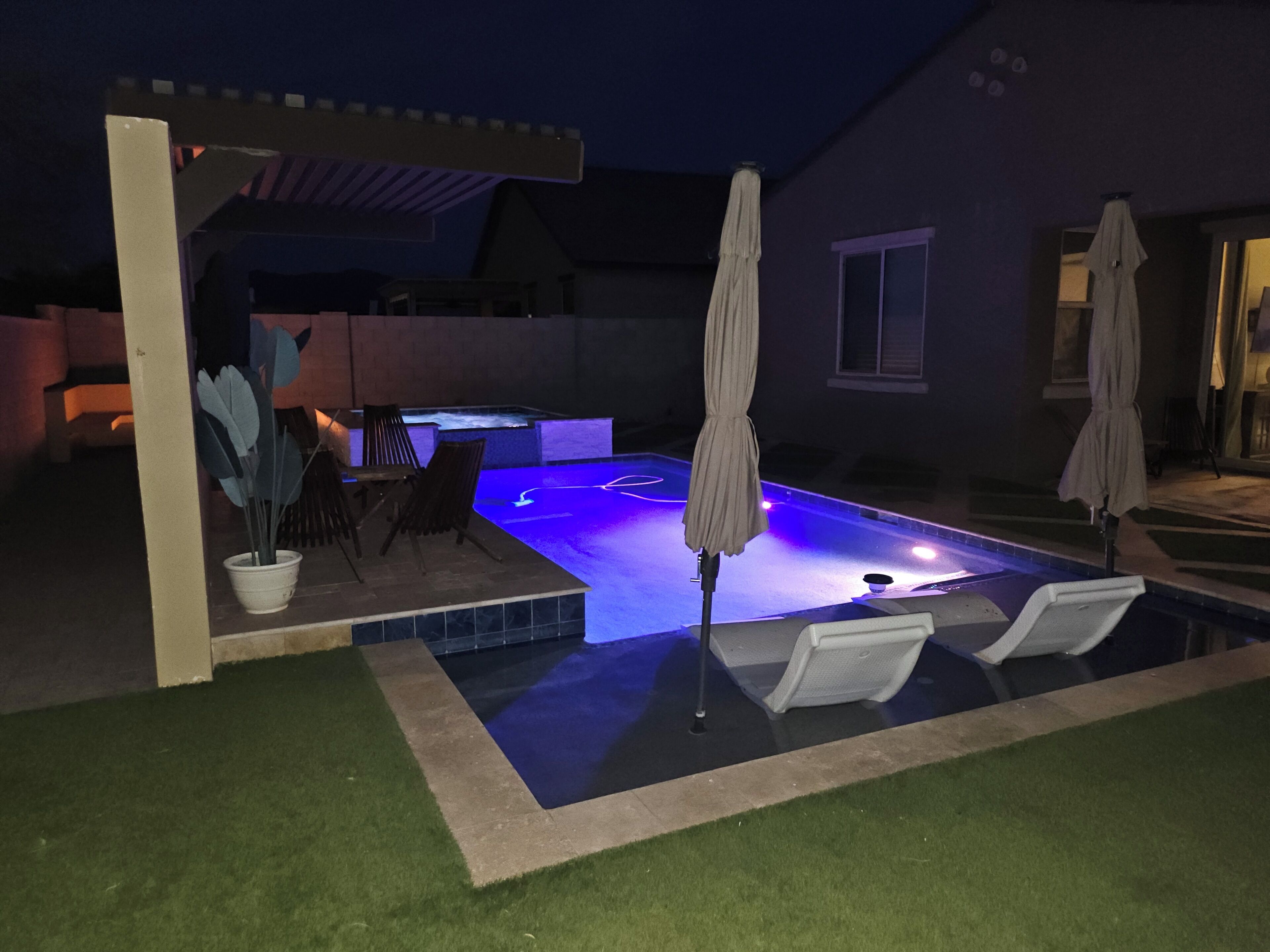 A swimming pool with a pergola and lounge chairs.