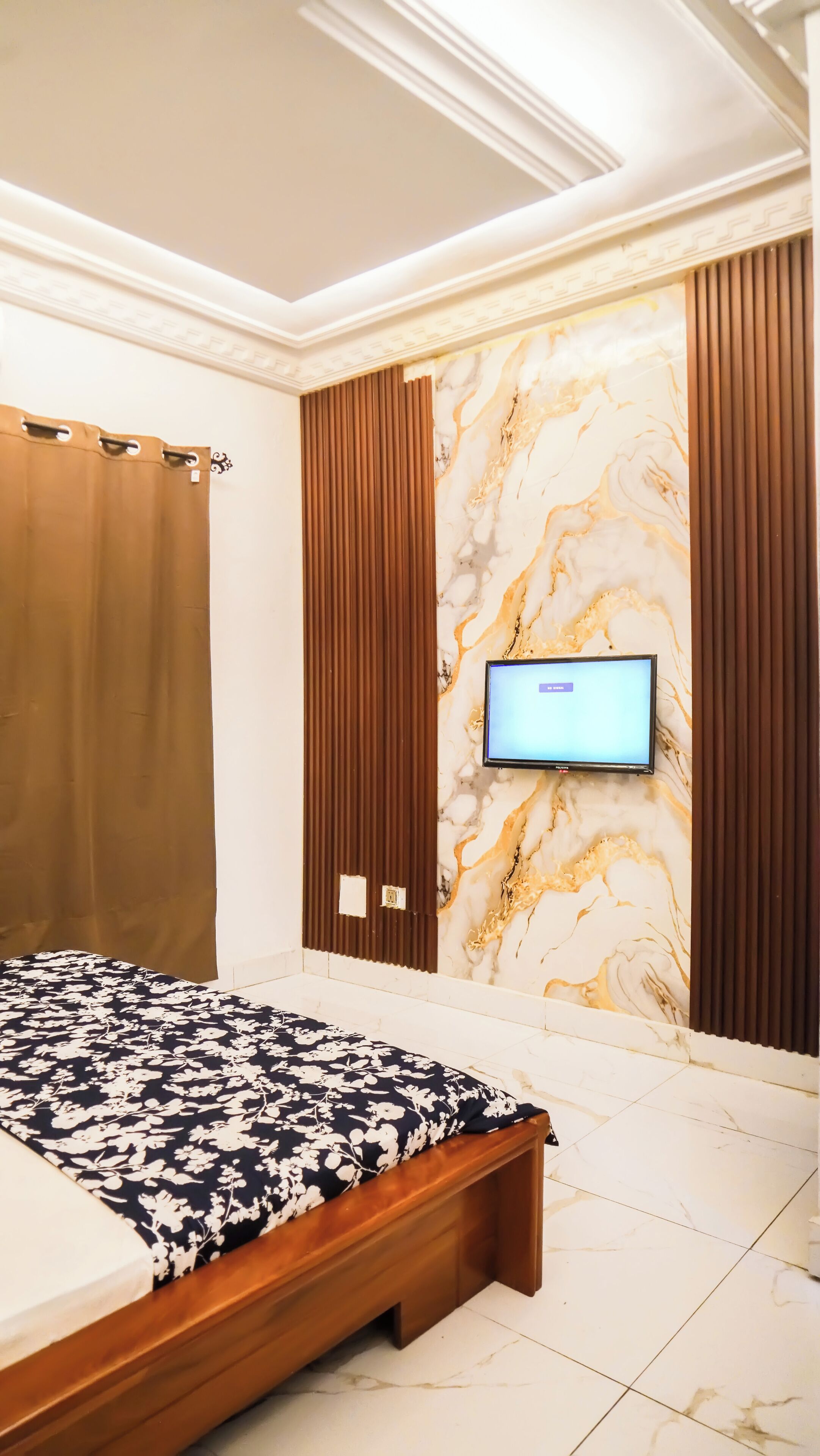 Une chambre à coucher avec un lit, un téléviseur fixé au mur en marbre et un décor mural en panneaux de bois.