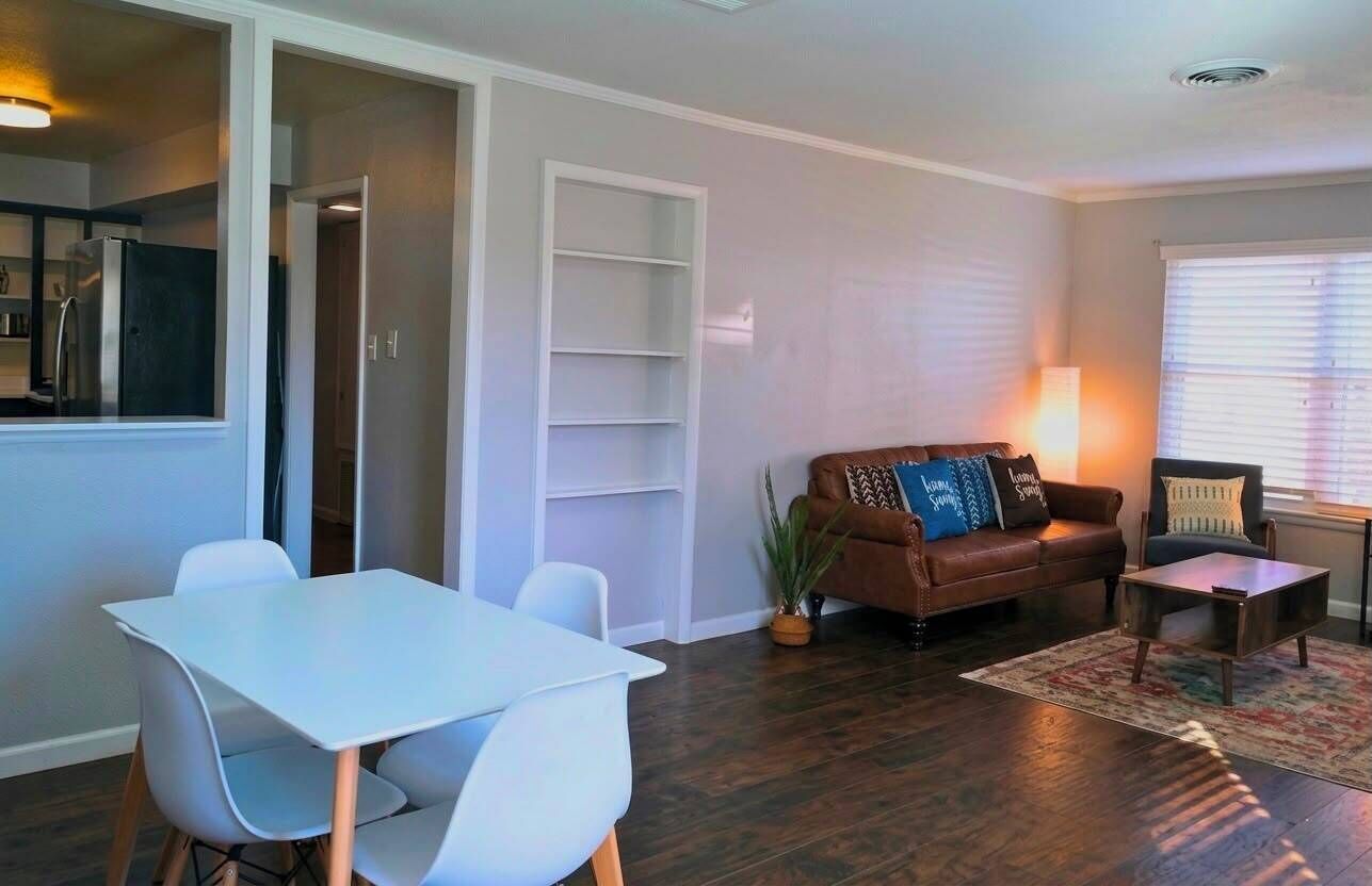 A living room with a brown sofa, a white table, and a small coffee table.
