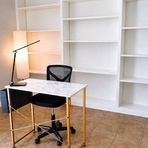 A workspace with a desk, chair, lamp, and shelving unit. - Spacious 4BR Home • 2 Kitchens • Sleeps 8 (Houston)