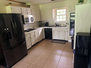 A kitchen with white cabinets, a black refrigerator, a microwave, and a dishwasher. -  Wooded 3BR • Kayaks & RV Parking • 3 Mi to Brady Mtn Marina (Royal)