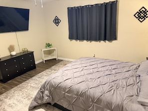 A bedroom with a bed, a dresser, a nightstand, and a wall-mounted TV. -  Wooded 3BR • Kayaks & RV Parking • 3 Mi to Brady Mtn Marina (Royal)