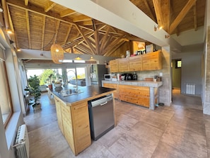 A spacious kitchen with wooden beams, a central island, and a view to the outdoors. - House of Worship (San Carlos de Bariloche)