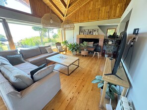 A modern living room with a wooden ceiling, a sofa, a coffee table, and a fireplace. - House of Worship (San Carlos de Bariloche)