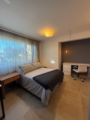 Un dormitorio con una cama, un escritorio y una silla.