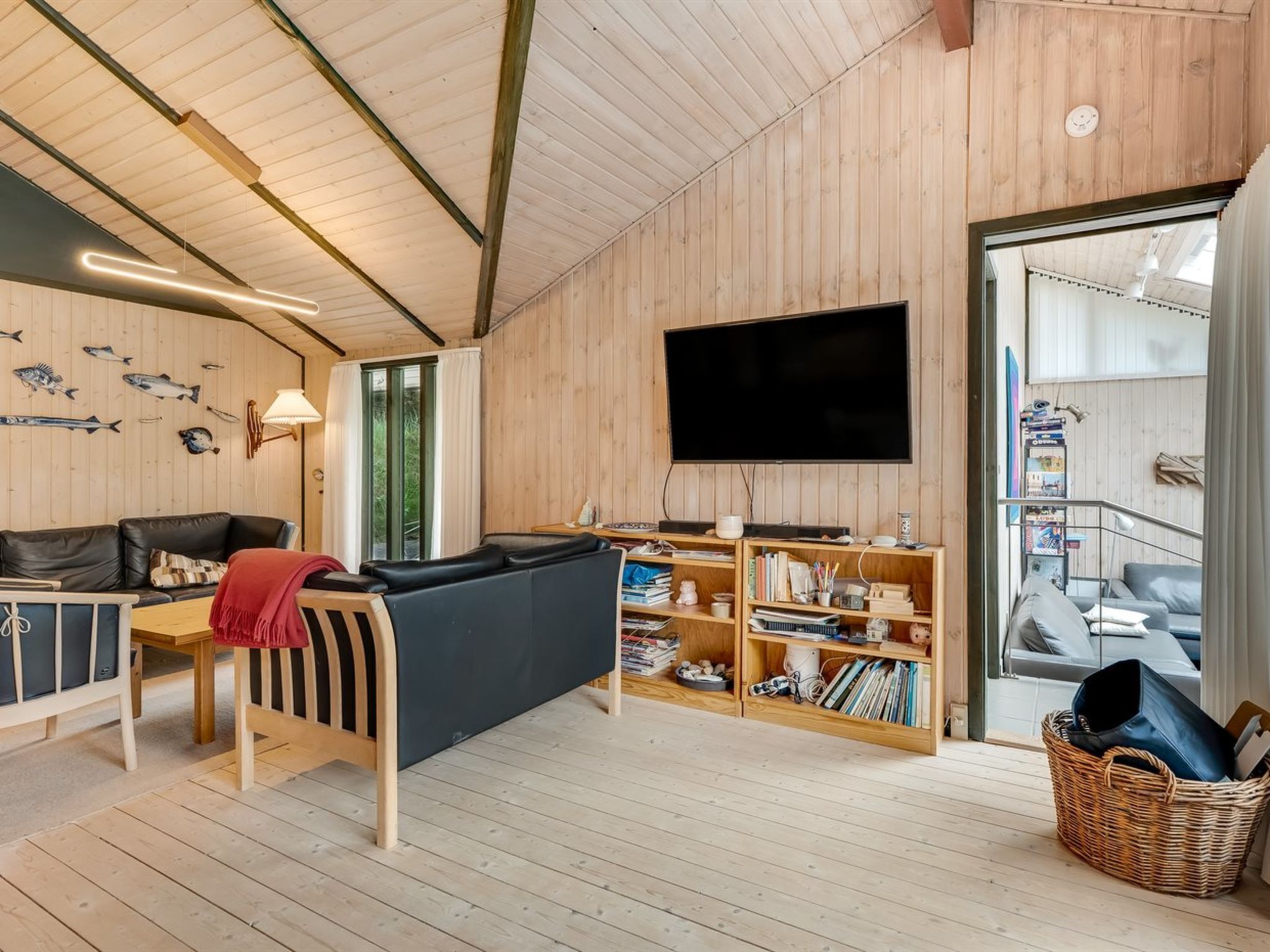 Una sala de estar acogedora con detalles de madera, un televisor de pantalla plana, un sofá, una mesita de centro y una estantería.