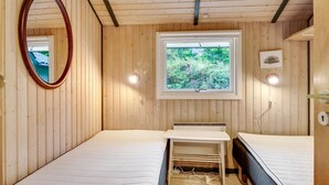 A small, cozy room with wooden walls and a single window. There are two beds, a mirror, and a small table with a heater. - "Nikoletta" - 150m from the sea by Interhome (Fjerritslev)