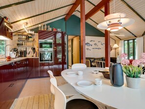 A modern kitchen with a dining area, wooden beams, and a view of the outdoors.
