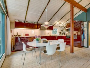 Eine moderne Küche mit Essbereich, Holzboden und einer Decke mit freiliegenden Balken.
